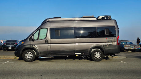 A sleek gray Ethos camper van, perfect for an RV rental, parked under a blue sky, ready for outdoor travel.