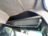 RV rental camper van interior featuring custom upholstered ceiling, overhead storage, lighting, and cabin details.