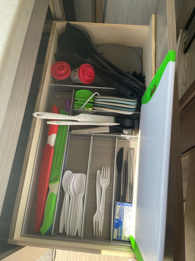 Organized kitchen drawer in an RV rental, featuring utensils, cutlery, salt/pepper shakers, and a cutting board for travel. — photo 16