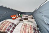 Cozy RV rental pop-top sleeping area with patchwork bedding, plush animals, and a warm camp vibe for your adventure.