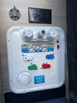This RV rental's utility panel features a Nautilus P4 water system, Zamp solar port, and electrical outlet for versatile hookups.