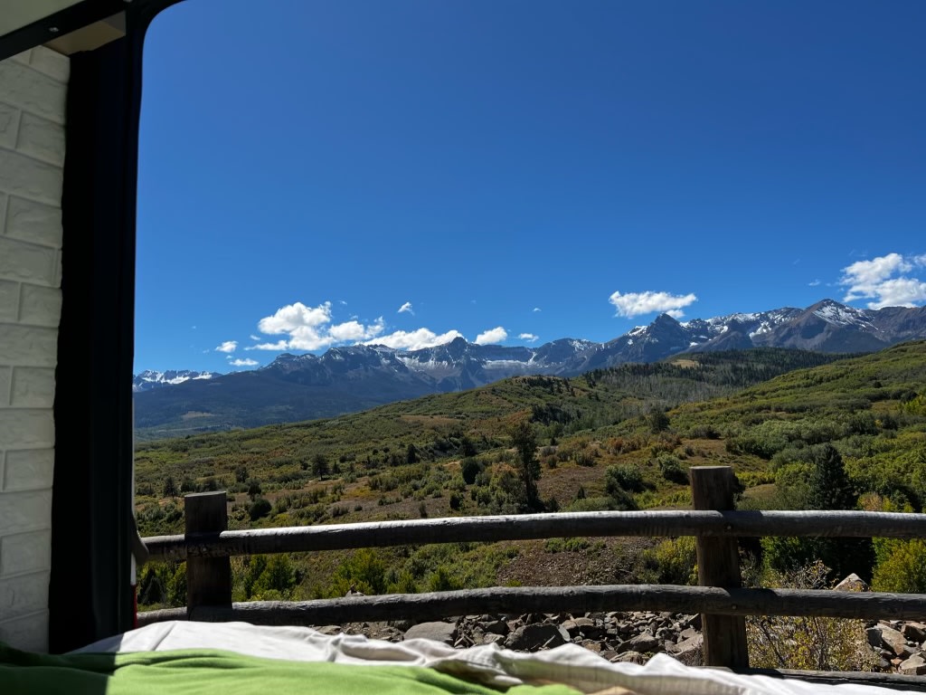  and a bright window view from a camper van's living space.|RV rental vehicle control panel displays battery — photo 13