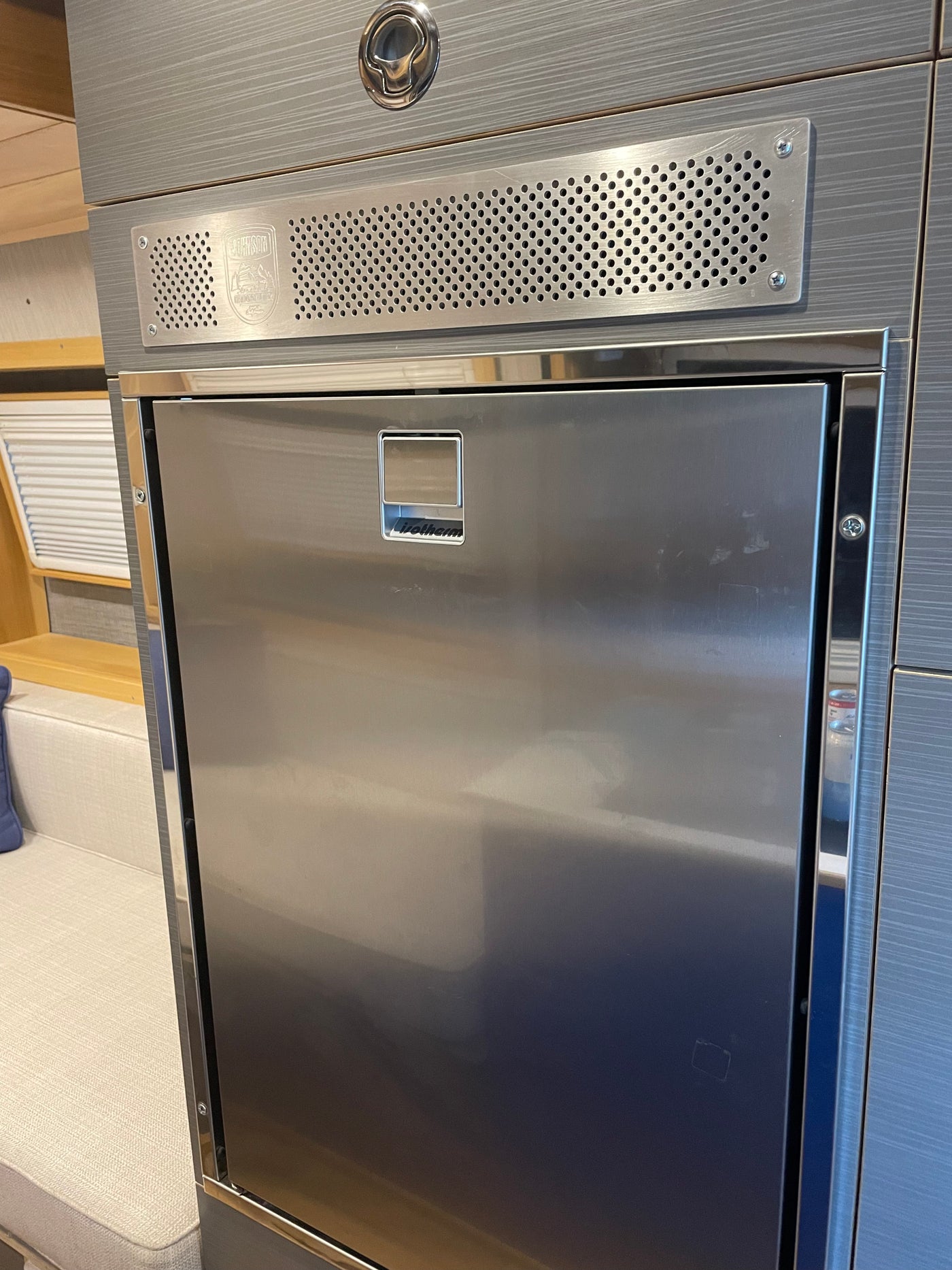 RV rental kitchen featuring a sleek, built-in stainless steel Isotherm refrigerator and upper vent panel. — photo 19