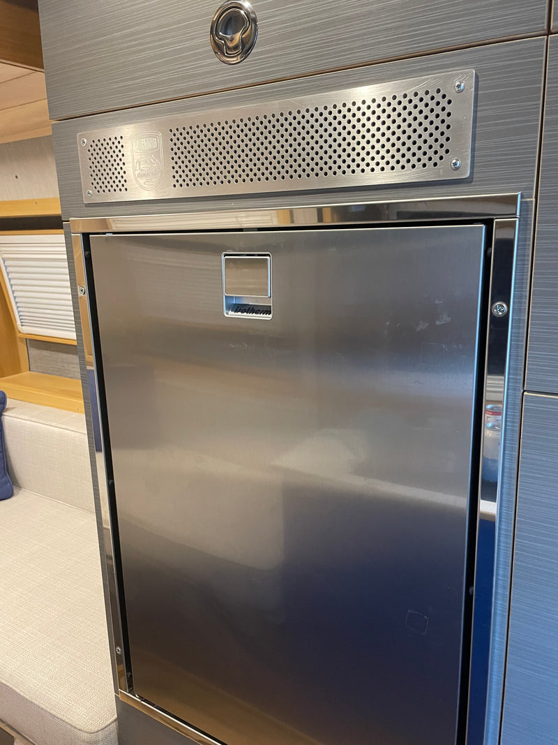 RV rental kitchen featuring a sleek, built-in stainless steel Isotherm refrigerator and upper vent panel. — photo 19