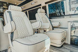 Luxurious RV rental interior featuring plush cream captain's chairs with diamond stitching, perfect for comfortable journeys.