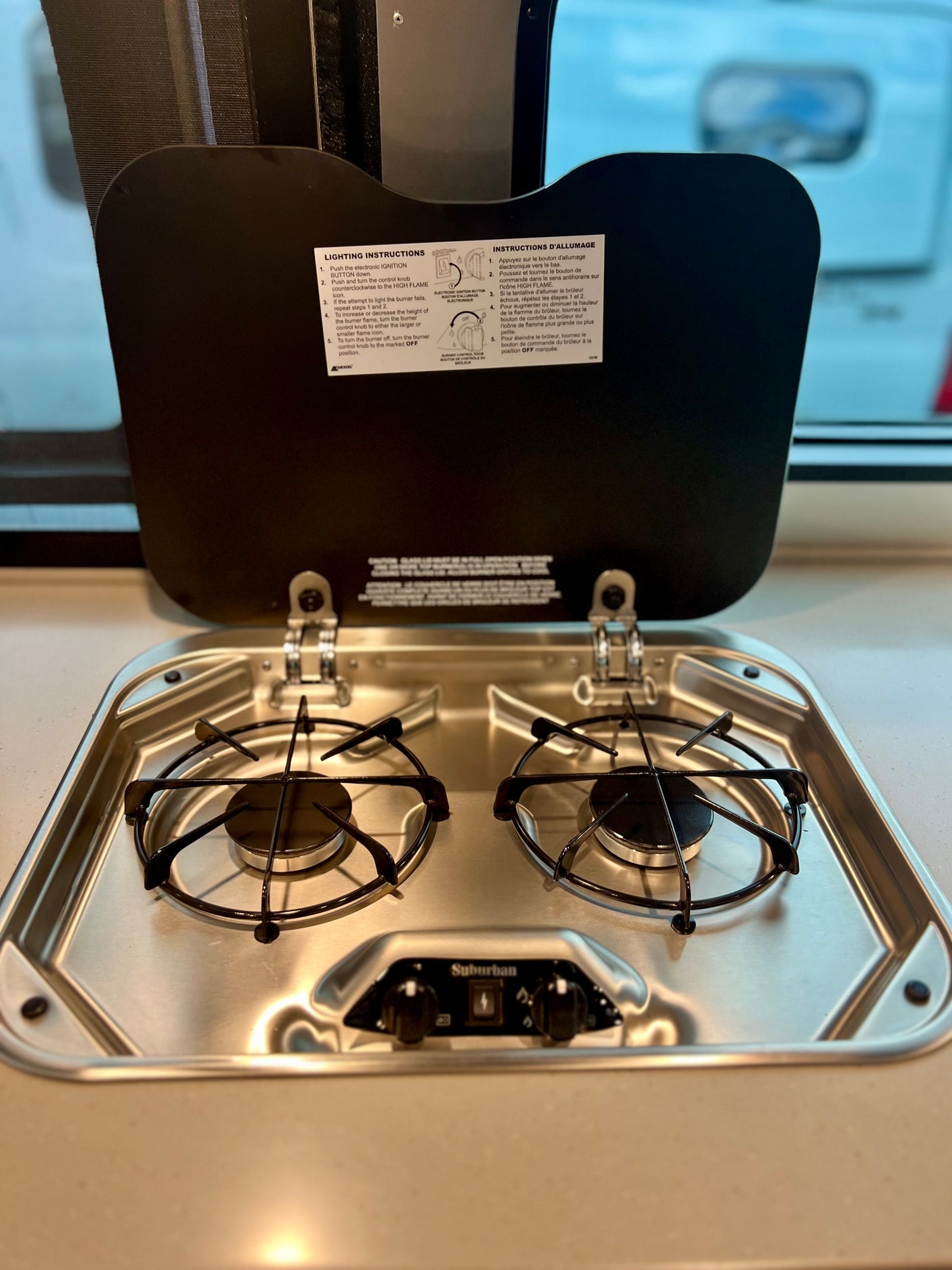 RV rental kitchen with a clean Suburban two-burner stovetop and lighting instructions for easy cooking.