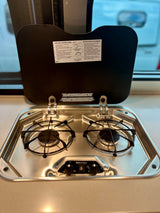 RV rental kitchen with a clean Suburban two-burner stovetop and lighting instructions for easy cooking.