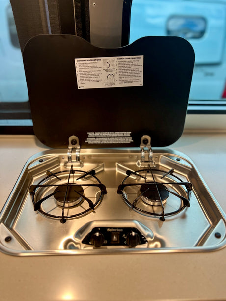 RV rental kitchen with a clean Suburban two-burner stovetop and lighting instructions for easy cooking.