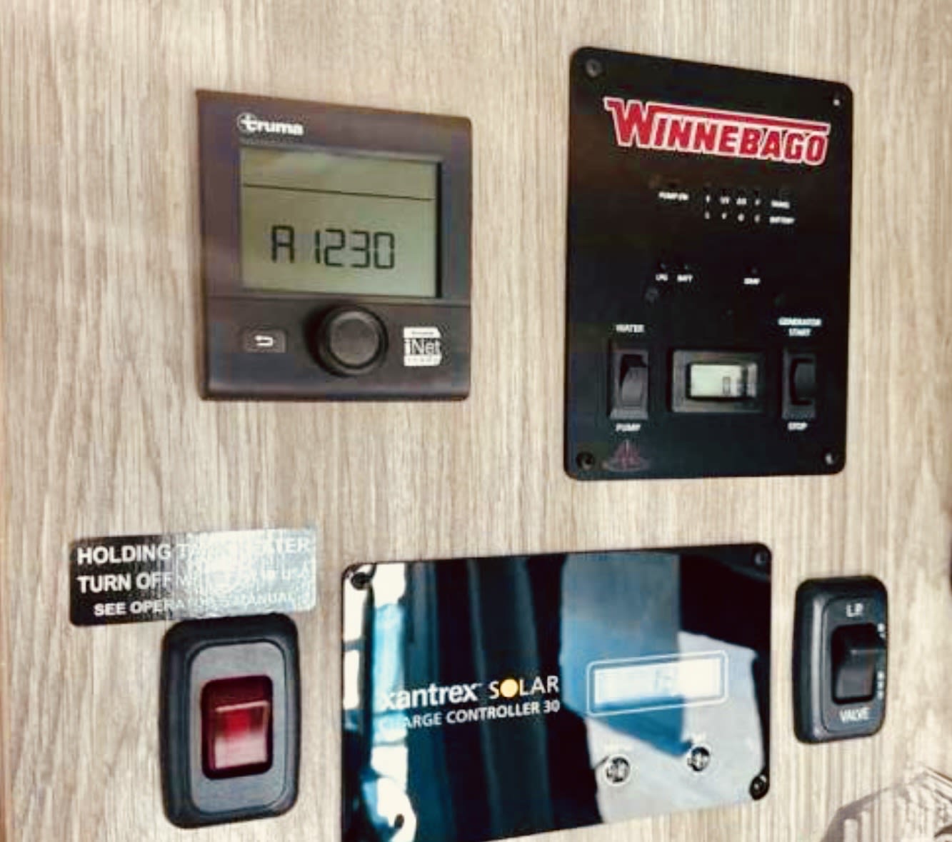 RV rental interior showing multiple control panels: Truma, Winnebago, Xantrex solar controller, and LP valve switch for essential RV functions.