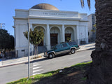 Green SUV parked near 'The Light House' building on a steep street. Consider an rv rental for your next journey.