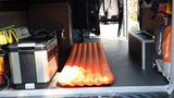 Inside an RV rental van: an orange sleeping pad, portable power, and camping bags, ready for adventure.