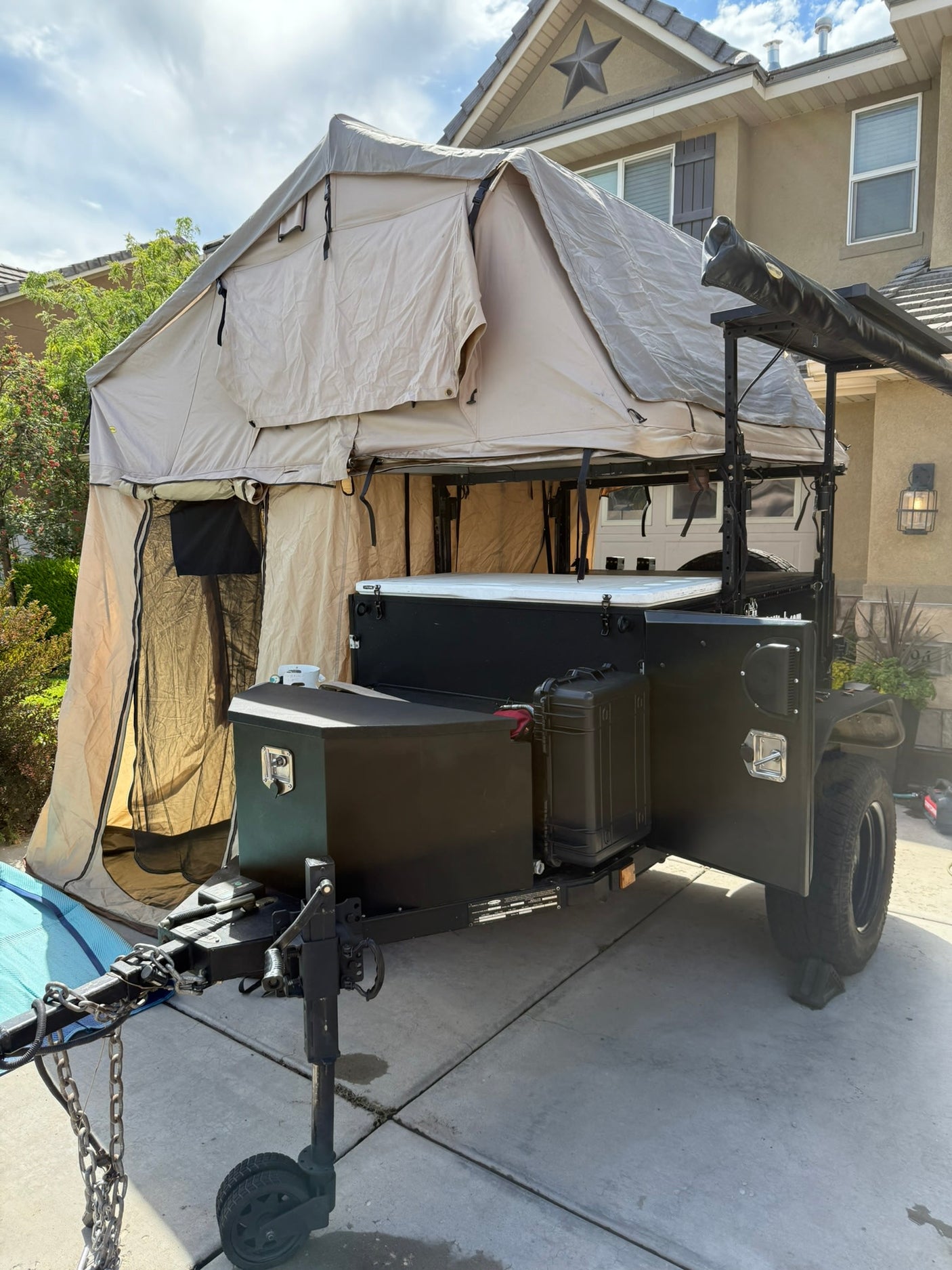 Off-road camping trailer with a fully deployed tan rooftop tent and annex. A rugged RV rental alternative for outdoor adventures.
