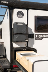 Side view of a white RV rental with a mounted water tank and a pull-out kitchen, ideal for outdoor trips.