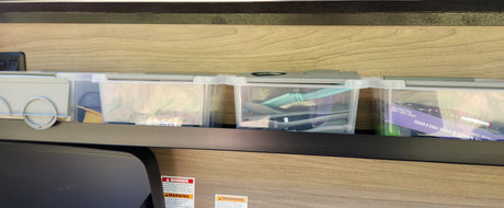 Organized RV rental kitchen storage: Clear containers on a shelf neatly hold cutlery, cooking utensils, and small essentials for travel.