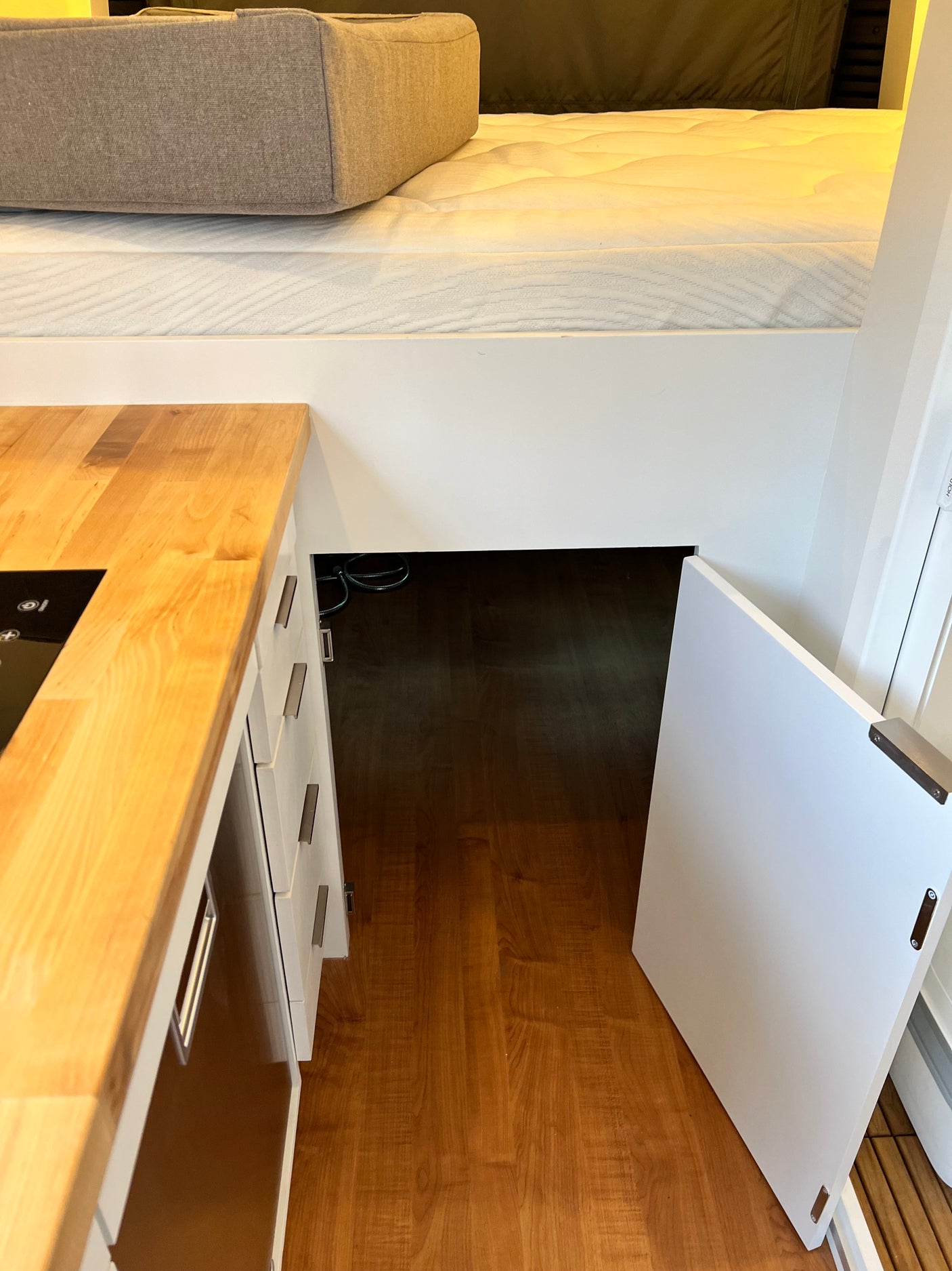 RV rental: Compact interior with a raised bed, modern kitchen counter, and under-bed storage accessible via an open door.