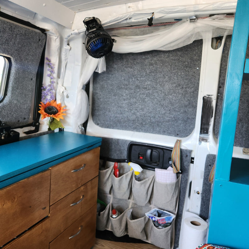 Inside an RV rental: a bright blue counter, wooden storage, and wall-mounted organizers create a functional, cozy van living space. — photo 18