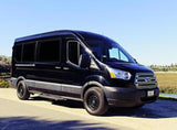 This black Ford Transit van, a spacious RV rental, is perfect for adventure. It's parked on pavement with a scenic outdoor background.