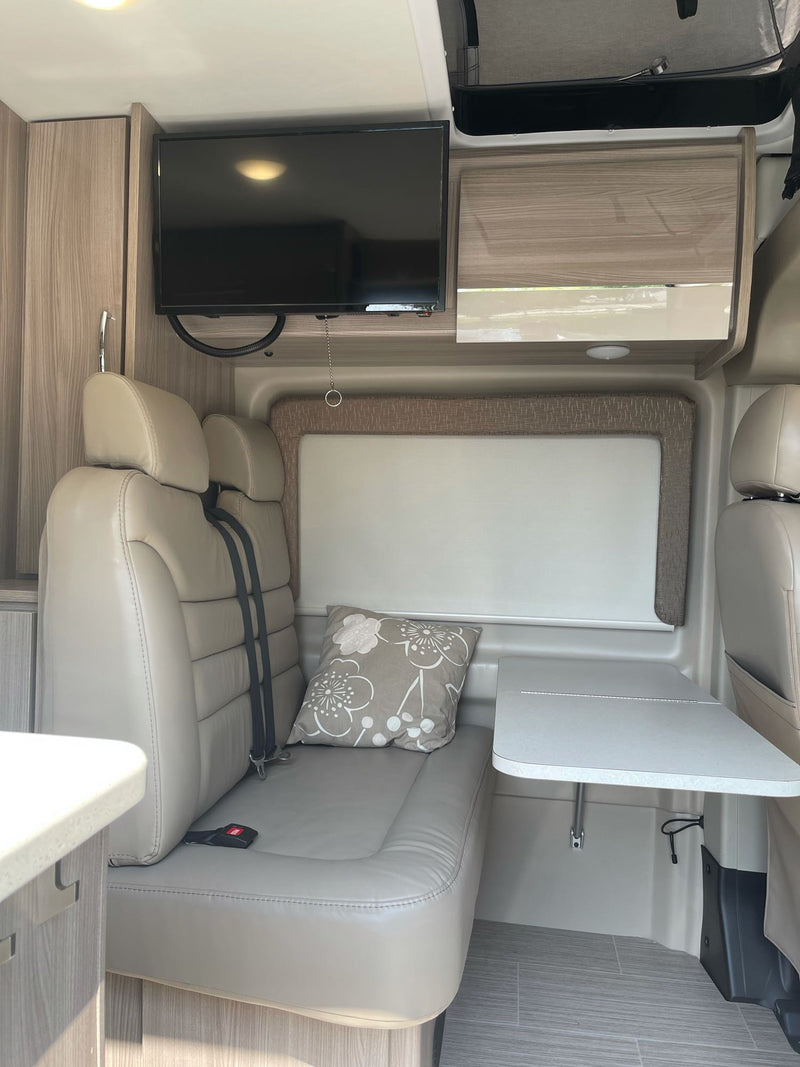 RV rental interior: beige seating, wall-mounted TV, and fold-down table. A comfy space for your next adventure. — photo 12