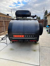 Rear of a black 'MODERN BUGGY' teardrop camper, featuring solar panels and a spare tire, ready for an RV rental adventure.