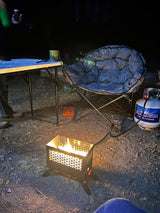 Cozy RV rental campsite at night: A portable gas fire pit, comfy chair, and table are set up for a warm outdoor evening.