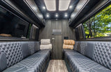 Premium RV rental interior featuring black diamond-stitched seating, wood paneling, and bright cabin lighting.