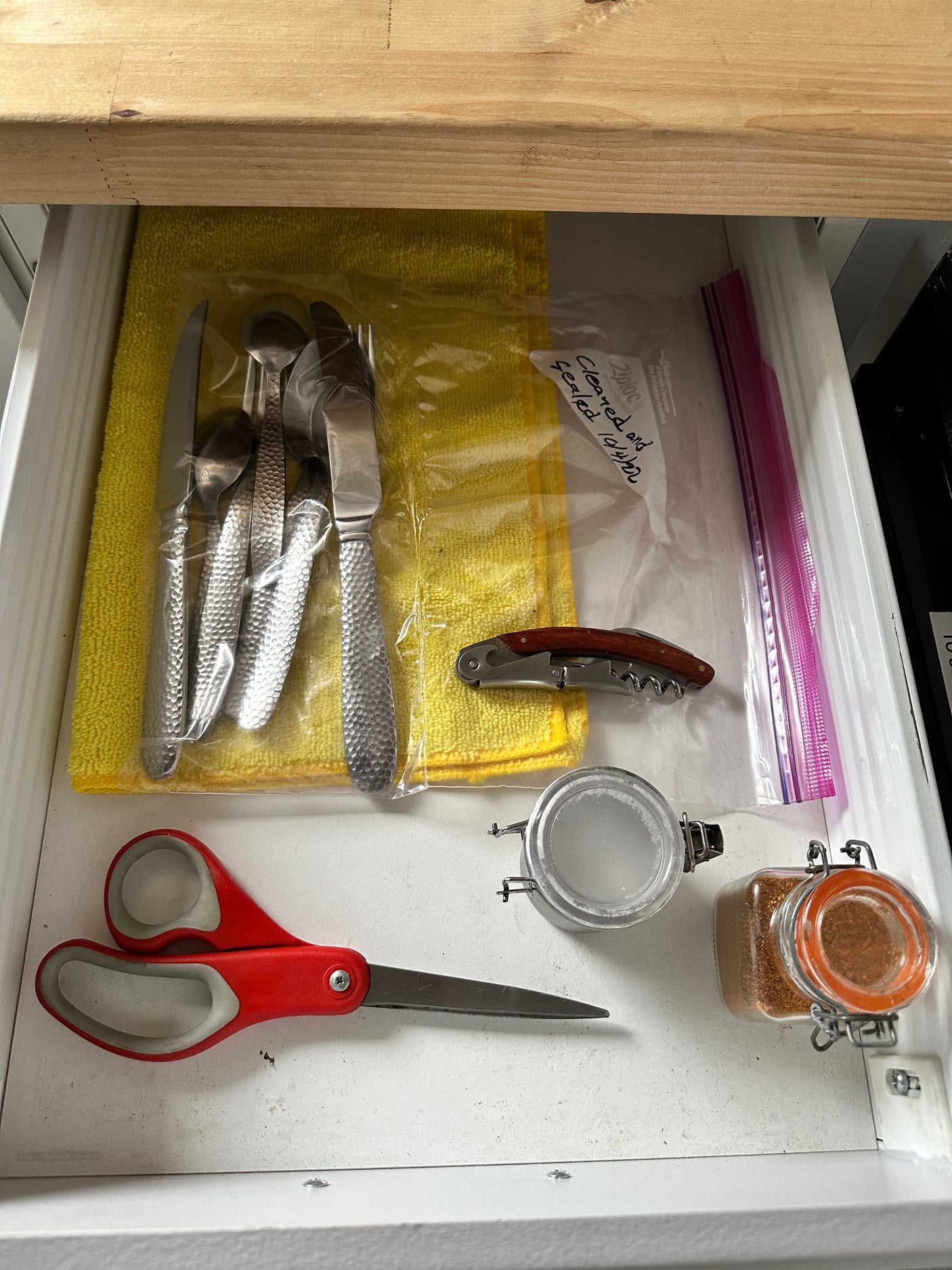 RV rental kitchen drawer storage: sealed cutlery, corkscrew, scissors, and spices neatly arranged for convenience.