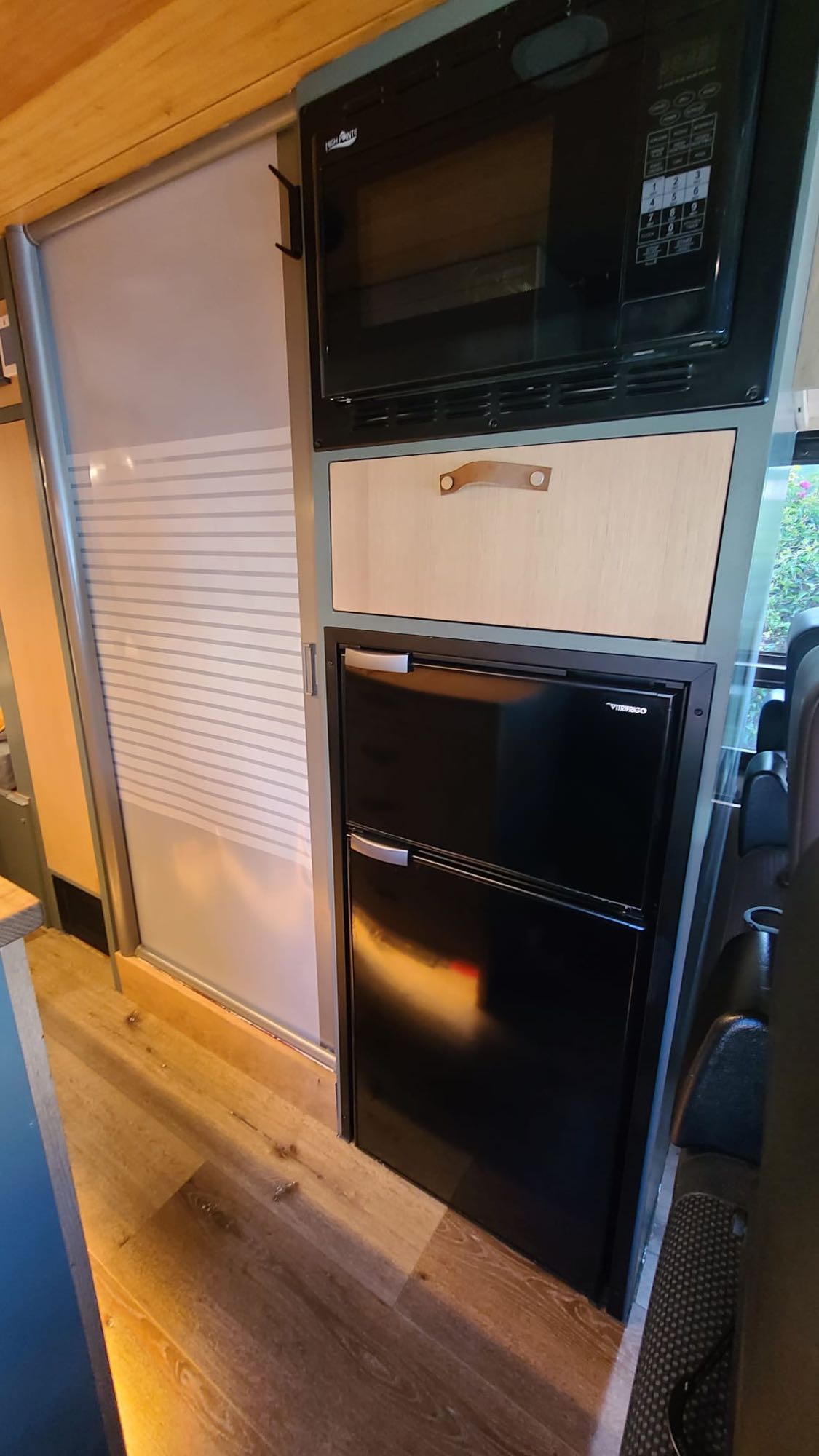  and warm wood finishes with ambient lighting.|Organized RV kitchen features an open drawer with utensils and a spice rack under bright lights — photo 14