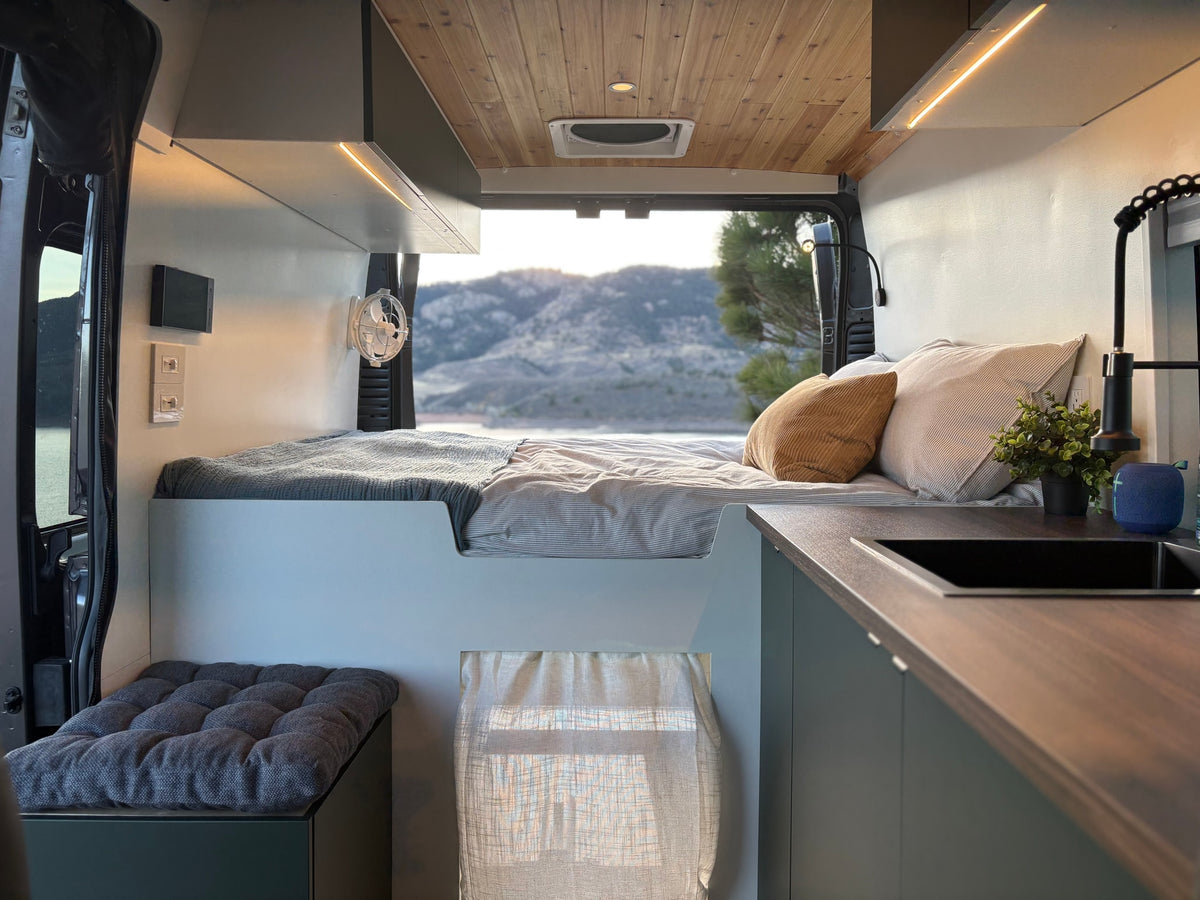 This stylish RV rental offers a modern camper van interior with a cozy bed, kitchen area, and scenic views. — photo 5