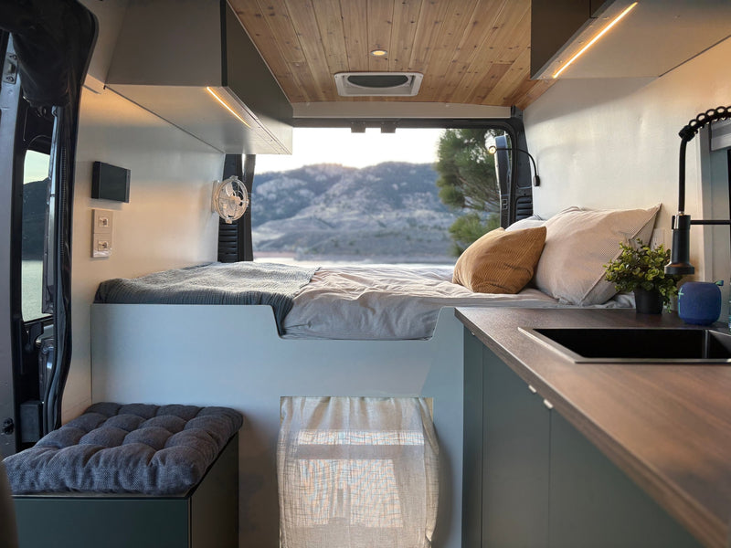 This stylish RV rental offers a modern camper van interior with a cozy bed, kitchen area, and scenic views. — photo 5
