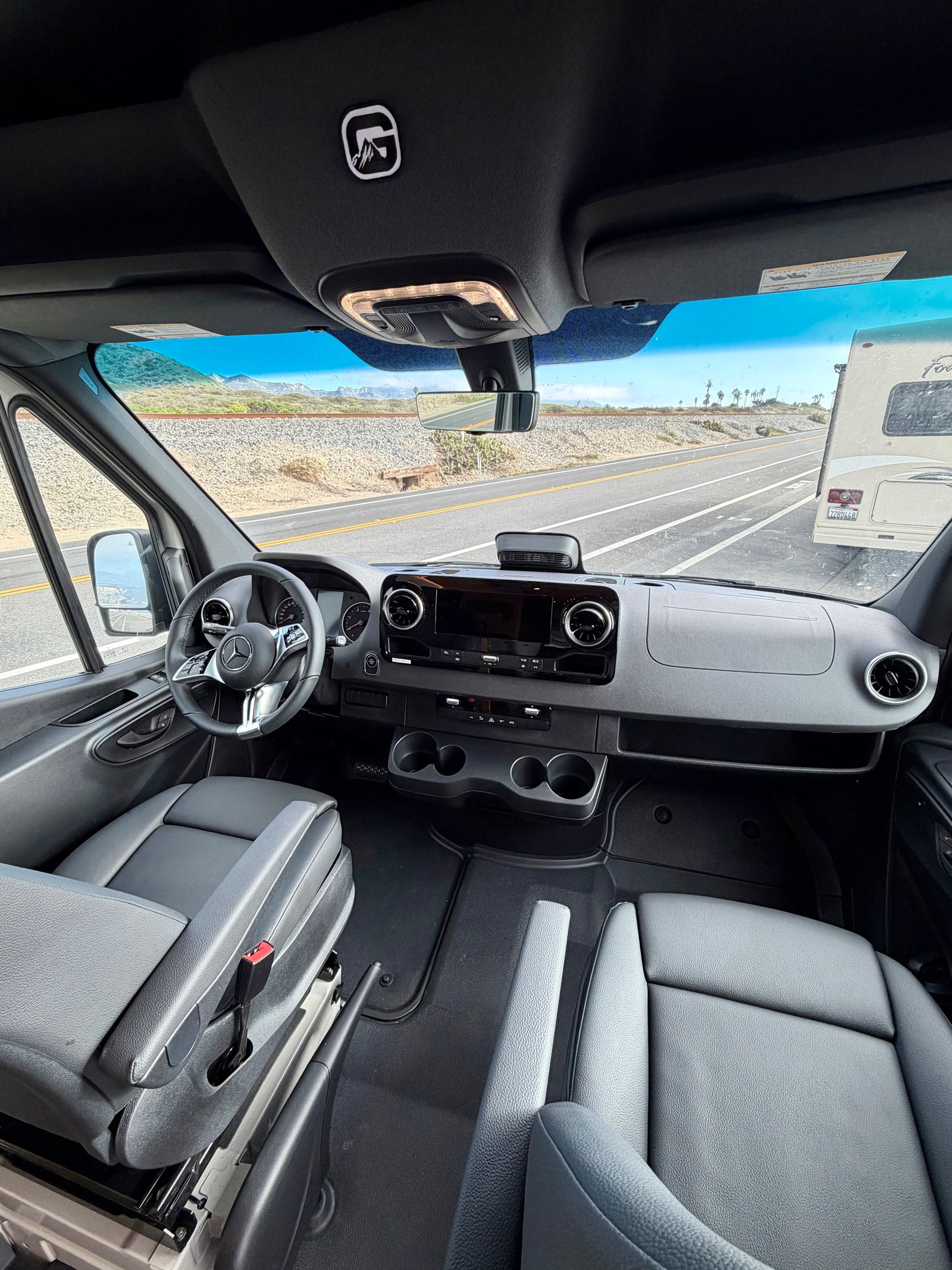 Inside an rv rental: View from the passenger seat shows the modern Mercedes-Benz cockpit, dashboard, and road ahead.