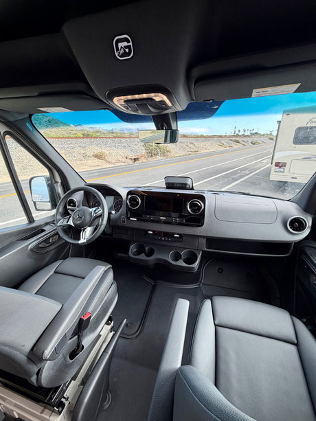 Inside an rv rental: View from the passenger seat shows the modern Mercedes-Benz cockpit, dashboard, and road ahead.