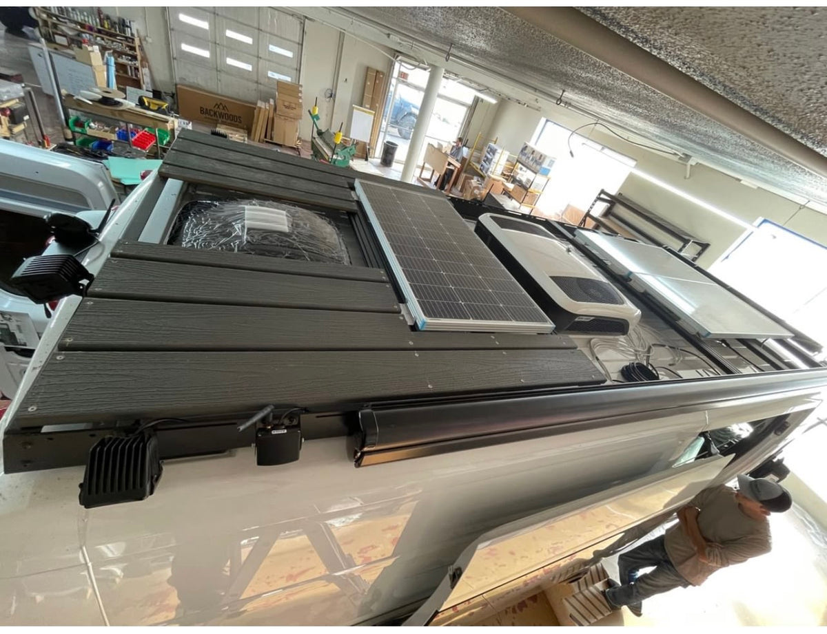  and discreet bathroom. Ready for adventure.|White RV rental rear view: equipped with a sturdy black ladder and a secure storage box for extra cargo.|Step inside this custom RV rental. Features include a compact kitchen — photo 11