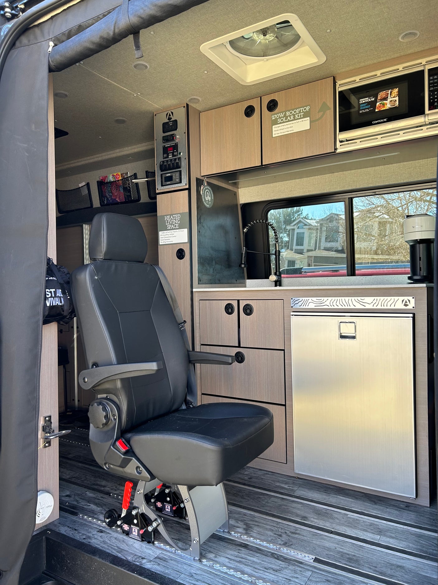 Spacious RV rental interior with swiveling seat, compact kitchen, and storage, perfect for adventure travel. Note the solar kit info.