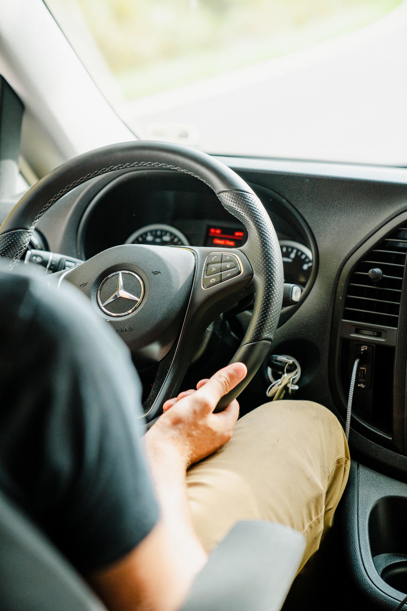 Inside an RV rental: a person's hands on the Mercedes-Benz steering wheel. The dashboard and blurred road ahead are visible, perfect for adventure.