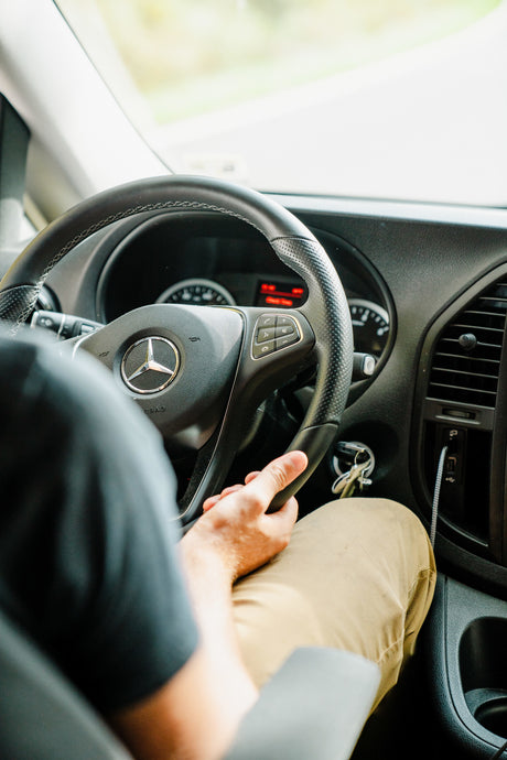 Inside an RV rental: a person's hands on the Mercedes-Benz steering wheel. The dashboard and blurred road ahead are visible, perfect for adventure.