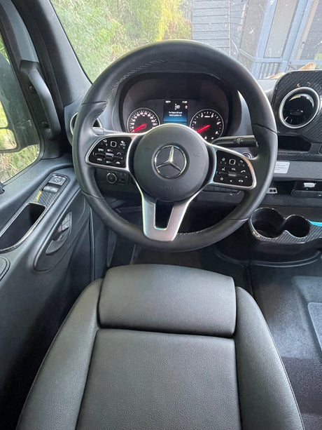 Inside a clean rv rental: Mercedes-Benz steering wheel, dashboard with 102°F, and comfortable driver's seat.