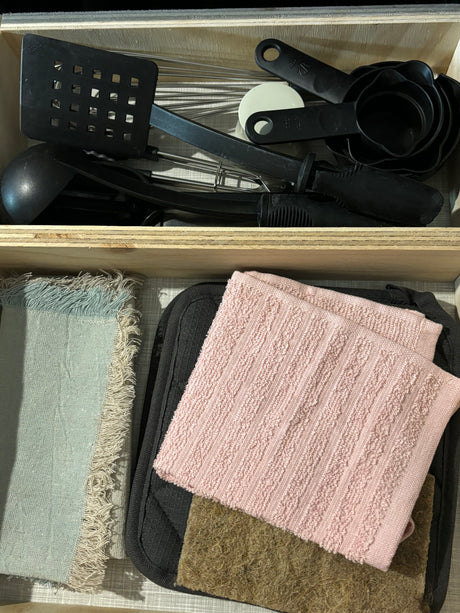 RV rental kitchen: Organized drawers hold black cooking utensils (spatula, whisks, measuring cups) and kitchen towels (including potholder).