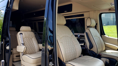 Plush RV rental interior featuring diamond-stitched tan leather seats, armrests, and spacious design.