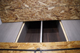 RV rental: Under-bed storage compartment revealed, featuring gray sliding doors, a metal divider, and OSB paneling.