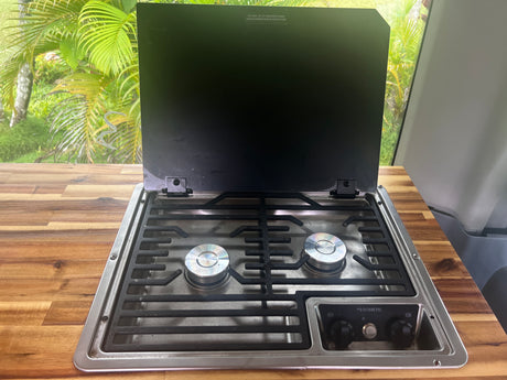 This RV rental features a Dometic two-burner camper stove with a raised cover, ideal for cooking on the go.