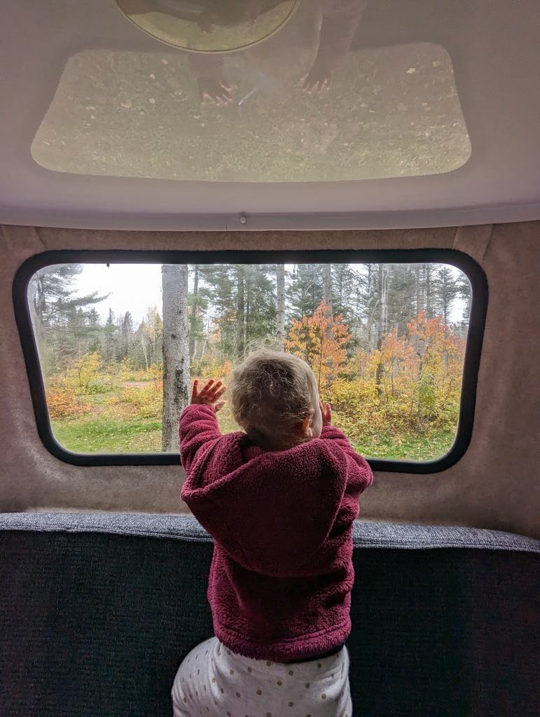  a small kitchen with a stove and kettle.|Compact RV rental interior featuring bunk bed