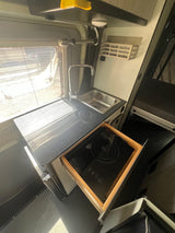 Compact kitchenette inside an rv rental, featuring a sink, countertop, and a pull-out true induction cooktop. Ideal for travel.