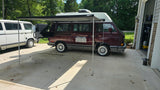 Maroon VW Westfalia camper van RV rental with deployed awning and rear grill. Ready for adventure!