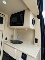 Experience comfort in this RV rental's modern kitchenette, featuring a microwave, sink, and sound system.