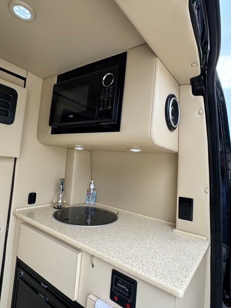 Experience comfort in this RV rental's modern kitchenette, featuring a microwave, sink, and sound system.