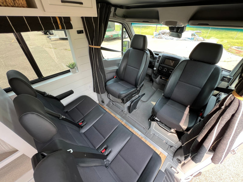 Spacious RV rental interior with black seating for multiple passengers, wood accents, and modern comforts. — photo 7
