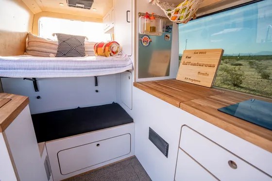  and accessories for organized campervan living.|This rv rental features a well-equipped van kitchen with an open fridge — photo 9
