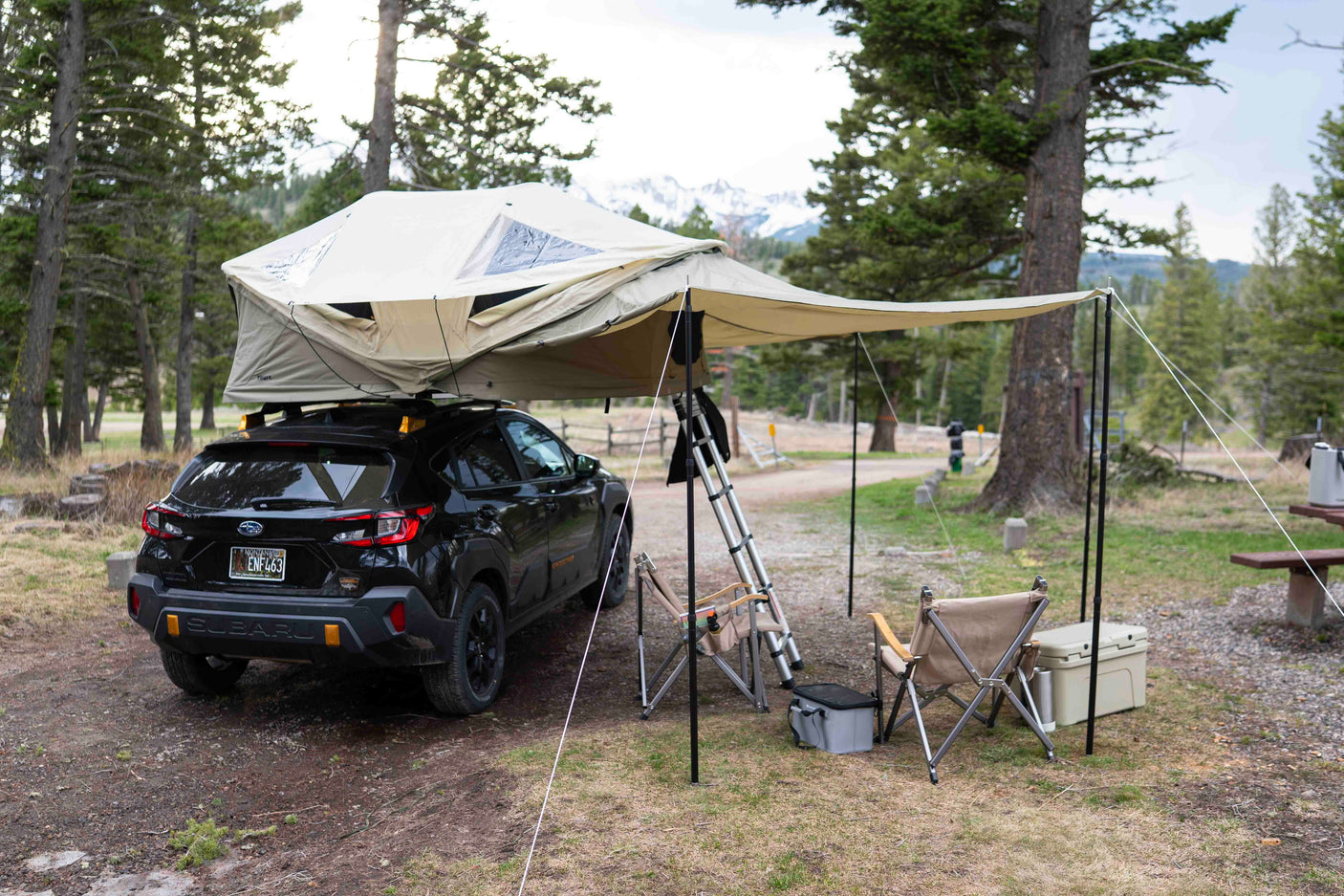 This Subaru, outfitted with a rooftop tent and awning, offers a unique car camping experience in a scenic campsite, a great RV rental alternative.