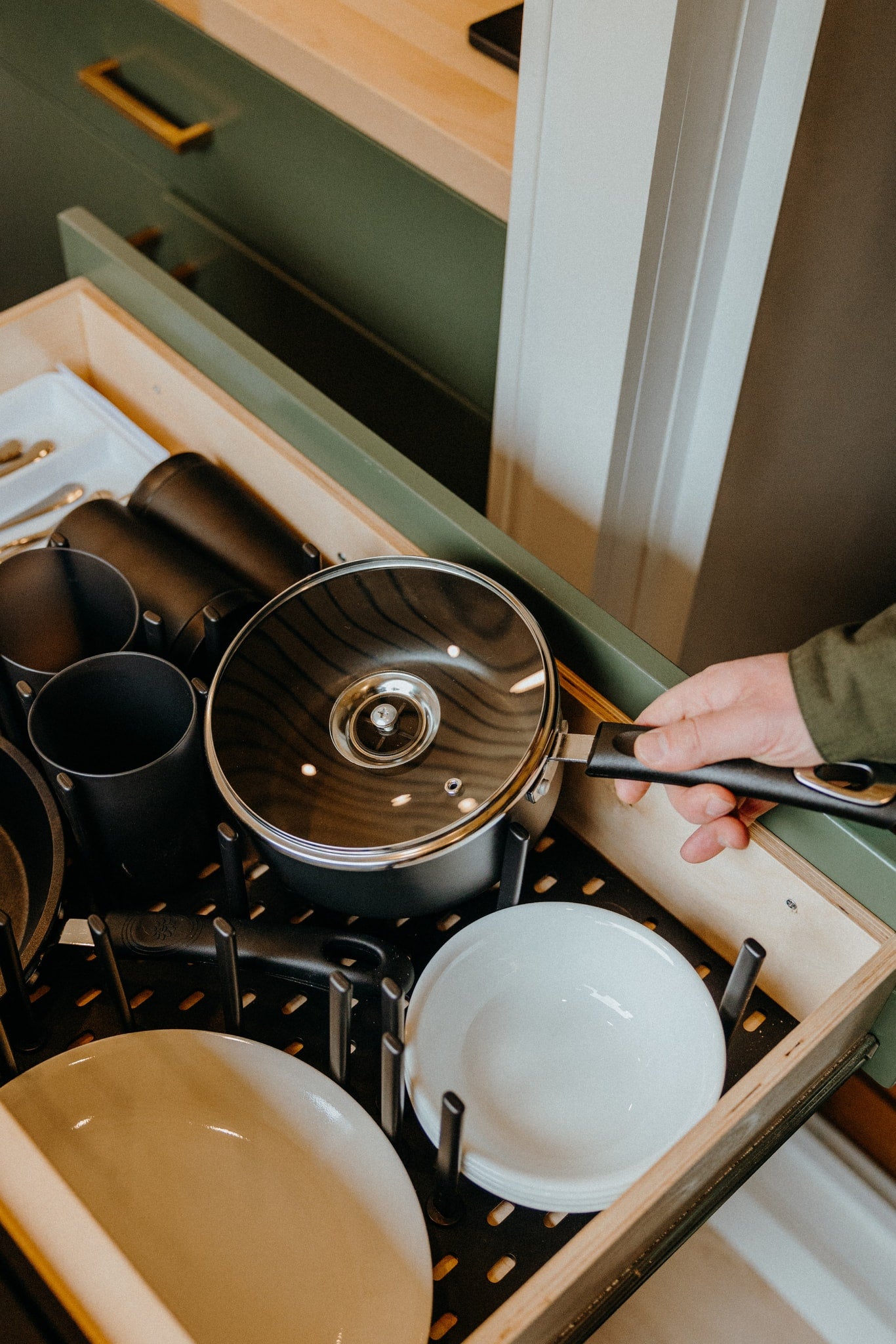 RV rental: Hand opens a kitchen drawer, showcasing organized pots, pans, and bowls in a smart storage system. — photo 8