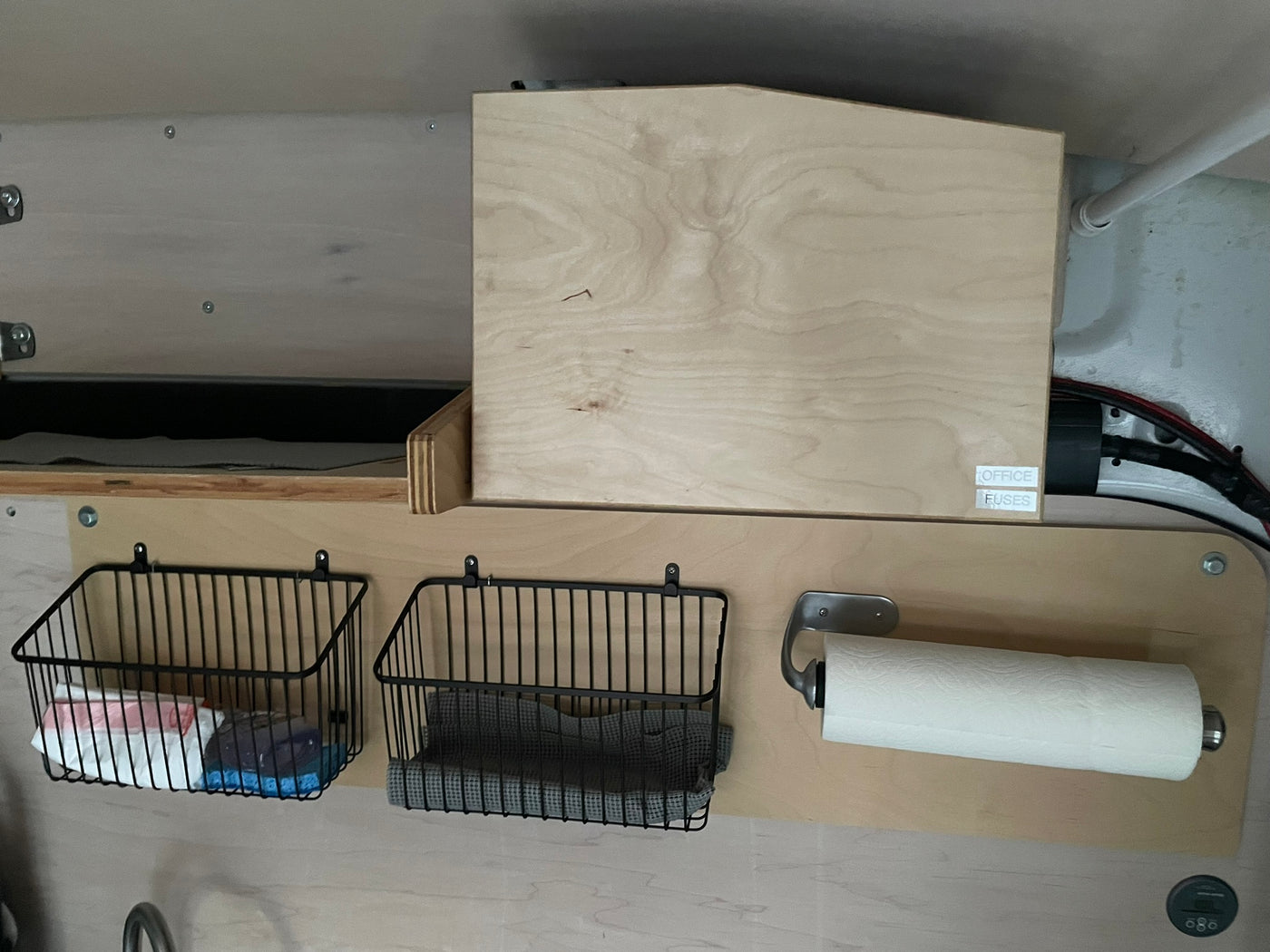RV rental utility area: wood paneling, hanging storage baskets, paper towel holder, and labeled "OFFICE FUSES" box. — photo 8